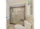 Bright bathroom with a tiled shower featuring sliding glass doors, a bench, and grab bars for accessibility at 452 Greenwich Nw Ave, Port Charlotte, FL 33952