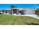 The exterior of this home has a well-manicured lawn, mature landscaping, and double car garage at 452 Greenwich Nw Ave, Port Charlotte, FL 33952