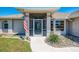 Welcoming front porch with stone details, complemented by an American flag and decorative front door at 452 Greenwich Nw Ave, Port Charlotte, FL 33952