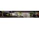 Well-lit home exterior at night, showcasing its manicured lawn, mature trees, and inviting entrance at 452 Greenwich Nw Ave, Port Charlotte, FL 33952