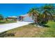 A well-maintained home exterior with a wide driveway and tropical palm trees at 452 Greenwich Nw Ave, Port Charlotte, FL 33952