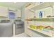 This laundry room features a washer and dryer, plenty of shelving, and tile floors at 452 Greenwich Nw Ave, Port Charlotte, FL 33952