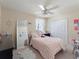 Bright bedroom featuring a pink bedspread, ceiling fan, large mirror, and a double-door closet at 11663 Anhinga Ave, Venice, FL 34292