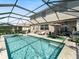 Beautiful screened pool with a spa, outdoor dining and lounging area, and lush landscaping at 11663 Anhinga Ave, Venice, FL 34292