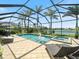 Inviting pool and spa area with screened-in lanai, lush landscaping, and serene lake views at 11663 Anhinga Ave, Venice, FL 34292