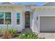 A welcoming front entrance features a glass door, sidelight, and brick walkway, surrounded by green plants at 14413 Heritage Landing Blvd, Punta Gorda, FL 33955
