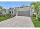 Charming single-story home with a well-manicured lawn, lush landscaping, and paver driveway under a clear blue sky at 14413 Heritage Landing Blvd, Punta Gorda, FL 33955