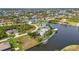 Aerial view reveals a waterfront property with a screened pool, private dock, and lush landscaping at 15490 Seafoam Cir, Port Charlotte, FL 33981