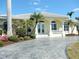 Stunning home entrance featuring a decorative driveway, lush landscaping, and a stylish front door with architectural pillars at 15490 Seafoam Cir, Port Charlotte, FL 33981