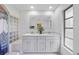 Well-lit bathroom featuring double sinks, a large mirror, shower with glass blocks and a window at 1556 Eagle St, Port Charlotte, FL 33952