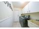 Bright laundry room with white cabinets, modern washer and dryer, utility sink, and tile floors at 1556 Eagle St, Port Charlotte, FL 33952