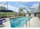 Inviting pool with a screened enclosure, featuring a patio area with comfortable seating and tropical scenery at 1556 Eagle St, Port Charlotte, FL 33952