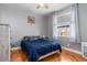 Comfortable bedroom with wood floors, a queen-size bed with blue comforter, and an overhead ceiling fan at 16450 Bauers Ave, Port Charlotte, FL 33954