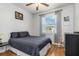 Well lit bedroom with hardwood floors, comfortable furniture, and a window overlooking the backyard at 16450 Bauers Ave, Port Charlotte, FL 33954