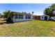 Large, grassy backyard featuring mature palm trees, a storage shed, and a view of the house at 182 Dowling Ne Ave, Port Charlotte, FL 33952