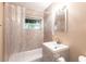 Bathroom featuring a shower-tub combo, tiled walls, a large window, and a single sink vanity at 182 Dowling Ne Ave, Port Charlotte, FL 33952