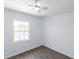 Minimal bedroom with hardwood floors, a ceiling fan, and a bright window, offering a clean and serene space at 182 Dowling Ne Ave, Port Charlotte, FL 33952
