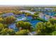 Aerial shot of the community pool, clubhouse, and tennis courts surrounded by lush, mature trees and landscaping at 19375 Water Oak Dr # 106, Port Charlotte, FL 33948