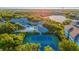 Overhead view of pool and tennis courts surrounded by mature trees and landscaping near lake and residences at 19375 Water Oak Dr # 106, Port Charlotte, FL 33948