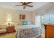 Comfortable bedroom with a ceiling fan, dresser, bedside table, and windows offering views of the surrounding area at 19375 Water Oak Dr # 106, Port Charlotte, FL 33948