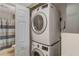 Laundry room featuring stacked washer and dryer appliances, with a bathroom partially visible through the door at 19375 Water Oak Dr # 106, Port Charlotte, FL 33948