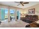 Inviting living room with plush carpeting, a ceiling fan, and sliding doors to a screened lanai with lake views at 19375 Water Oak Dr # 106, Port Charlotte, FL 33948