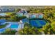 Aerial view of community pool, clubhouse, and tennis courts, with vibrant landscaping and surrounding trees at 19375 Water Oak Dr # 106, Port Charlotte, FL 33948