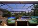 Outdoor oasis featuring a sparkling pool, hot tub, screened enclosure, and cozy seating area with fire table at 211 Lido Dr, Punta Gorda, FL 33950