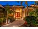 Inviting front entrance with vibrant red double doors, lush tropical landscaping, and a curved walkway at 211 Lido Dr, Punta Gorda, FL 33950