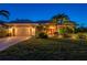 Beautiful home at dusk, featuring a lush lawn, tropical landscaping, and a vibrant red front door at 211 Lido Dr, Punta Gorda, FL 33950