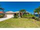Charming single-story home with lush landscaping, mature palm trees, and a vibrant red front door at 211 Lido Dr, Punta Gorda, FL 33950