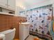 This bathroom features a colorful shower curtain, tiled walls, and white fixtures at 21444 Higgs Dr, Port Charlotte, FL 33952