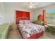 Bright bedroom with a floral comforter, ceiling fan, and orange curtains at 21444 Higgs Dr, Port Charlotte, FL 33952
