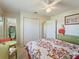 This bedroom features a ceiling fan, closet, an adjacent bathroom, and a floral comforter at 21444 Higgs Dr, Port Charlotte, FL 33952