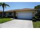 Well-maintained single-story home with a two-car garage, lush landscaping, and a clear blue sky at 24141 Green Heron Dr # 23, Punta Gorda, FL 33980