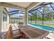 Inviting screened pool patio with dining table and view of the sparkling swimming pool and lush landscaping at 2427 Carnation Ct, North Port, FL 34289