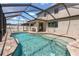 A freeform pool is surrounded by brick pavers and a large screened enclosure at 2427 Carnation Ct, North Port, FL 34289