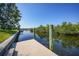 A concrete dock sits on calm canal waters with lush vegetation on the far bank under a clear blue sky at 3513 Dileuca St, Punta Gorda, FL 33950