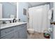 Updated bathroom featuring blue vanity with marble countertop and shower with white curtain at 3520 Kenneth Rd, Port Charlotte, FL 33953