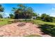 Landscaped backyard featuring a brick firepit and lush green grass with a view of the screened-in back porch at 3712 Balboa Ct, Punta Gorda, FL 33983