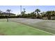 Outdoor tennis court with net and green surface, surrounded by lush palm trees and greenery at 4000 Bal Harbor Blvd # 124, Punta Gorda, FL 33950