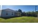 Green backyard with the home's back elevation featuring windows and a covered patio at 4071 Conestoga St, Port Charlotte, FL 33948