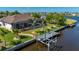 Aerial shot featuring a waterfront home with a screened lanai, pool, private dock, and lush landscaping at 4174 Perch Cir, Port Charlotte, FL 33948