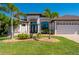 Well-manicured home featuring a three-car garage, tropical landscaping, and a paver driveway at 4174 Perch Cir, Port Charlotte, FL 33948