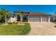 Beautiful single-story home featuring lush landscaping, a paver driveway, and a spacious three-car garage at 4174 Perch Cir, Port Charlotte, FL 33948