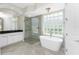 Luxurious bathroom boasting a freestanding tub, glass shower, and bright glass block window at 4676 Tuscana Dr, Sarasota, FL 34241