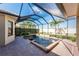 Screened-in pool area features a brick patio, tropical plants, and a clear view of the sky above at 4676 Tuscana Dr, Sarasota, FL 34241