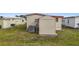 Tan home exterior showcasing the yard and a utility shed, perfect for storage at 5488 Holiday Park Blvd, North Port, FL 34287