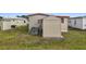 Tan home exterior showcasing the yard and a utility shed, perfect for storage at 5488 Holiday Park Blvd, North Port, FL 34287