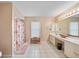 Neutral bathroom with dual vanities, tile floors, and a walk-in shower with a floral curtain at 657 Hartford Nw Dr, Port Charlotte, FL 33952